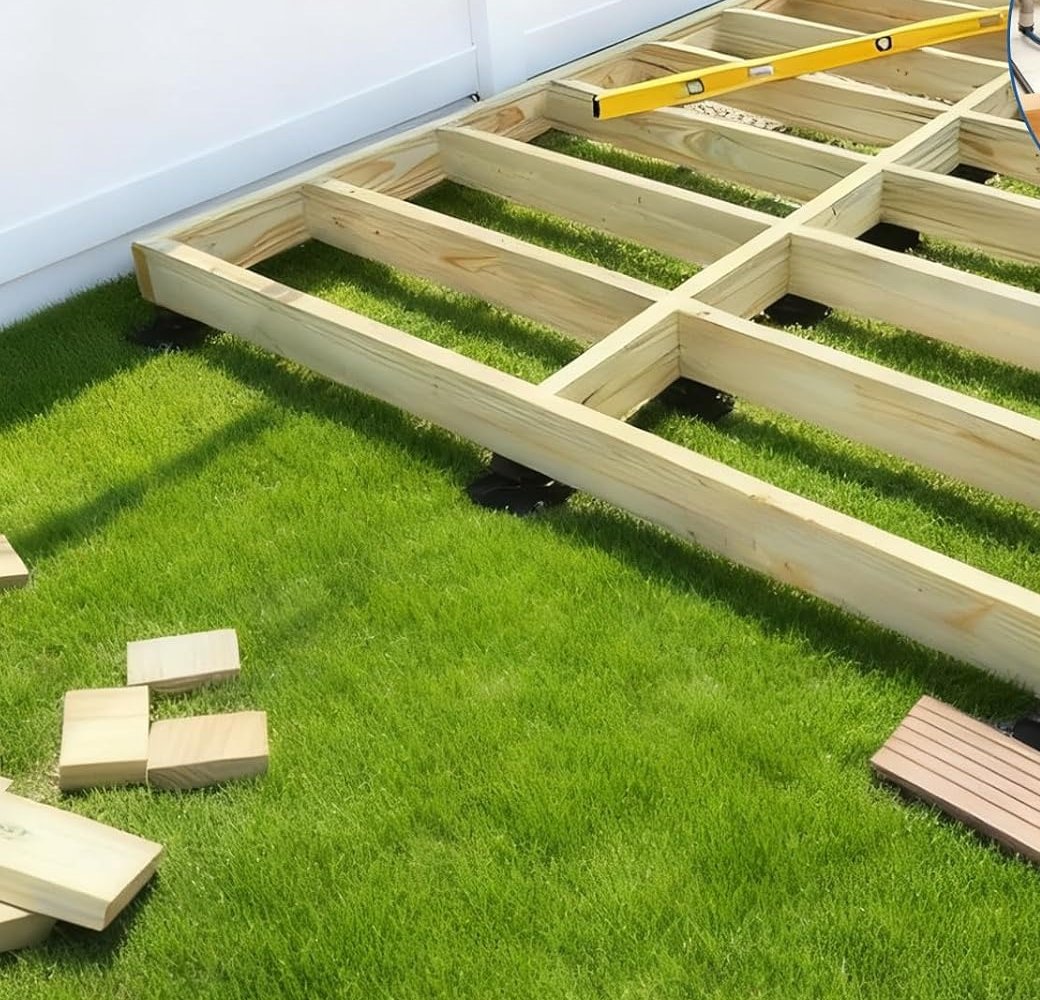 Black adjustable deck pedestals supporting timber joists on a low floating deck